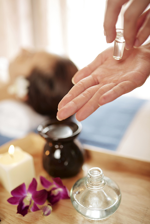 Hands of cosmetologist using essential oils for rejuvenating face massage