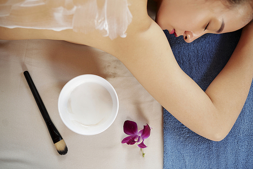 Young Asian woman relaxing in spa salon with moisturizing mask on her back