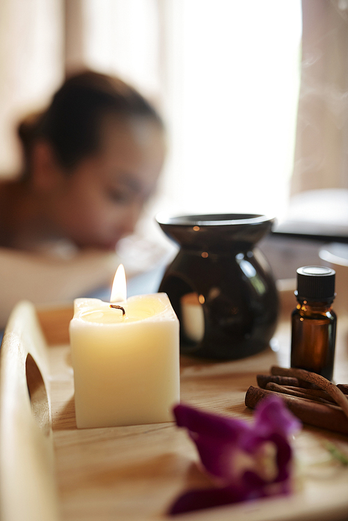 Burning candle and essential oil and other decor in luxurious spa salon