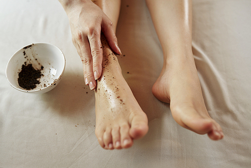 Close-up image of woman massaging feet with coffee scrub