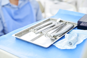 Close-up of dental instruments on tray on the table with patient in the background in dental clinic
