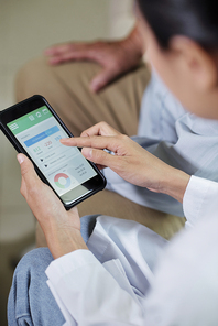 Close-up of female doctor holding mobile phone and examining the results of her patient in special medical application