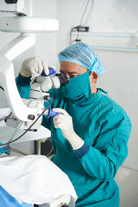 Surgeon in uniform working with operating system of laser vision correction in the operating room