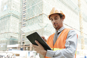 Professional construction engineer using application on tablet computer when working at site