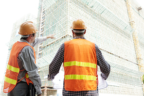 Two professional contractors discussing process of building at construction site