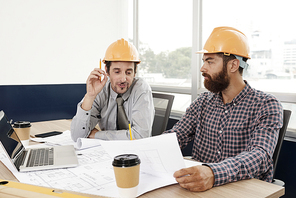 Architect telling his boss that the building blueprint needs to be changed at meeting