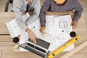 Civil engineers discussing information on laptop screen and sharing ideas, view from above