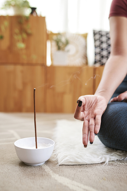 Meditating woman using aroma stick when meditating and practicing yoga at home