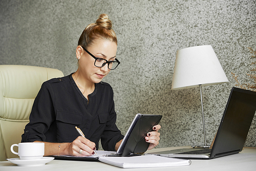 Pretty businesswoman wearing hair in bun when filling personal information on contract