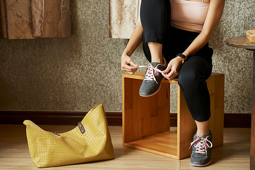 Cropped image of woman sitting of wooden box and wearing sneakers