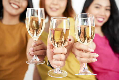 Close-up of female friends holding glasses with sparkling wine and celebrating