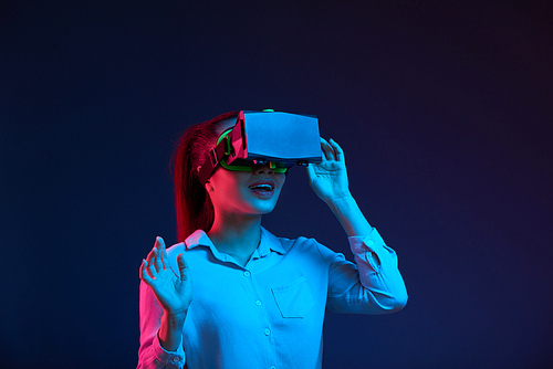 Positive young Asian business lady in virtual reality goggles testing new application