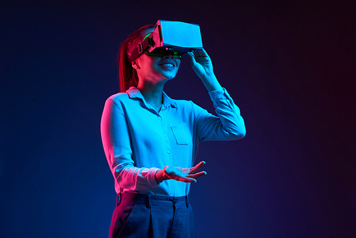 Young cheerful business lady talking when wearing virtual reality headset with application for business meetings