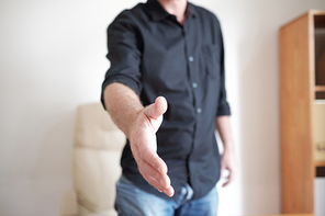 Close-up of businessman standing at office and stretching his hand for handshake