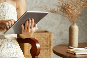 Woman sitting on armchair and reading articles on digital tablet