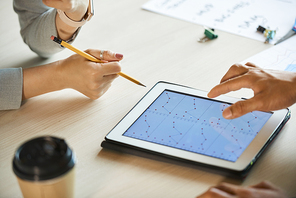 Hands of entrepreneurs discussing charts on tablet computer at meeting