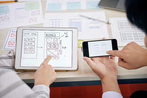Contemporary technical developers discussing digital schemes of new gadget version in touchpad and smartphone