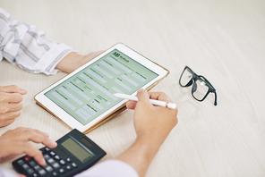Two contemporary auditors discussing points of application form of credit report in touchpad and making calculations