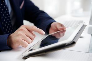 Close-up of businessman touching the display of digital tablet while working at the table at office