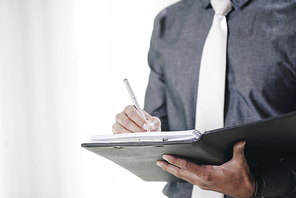 Close-up image of businessman signing contracts in folder