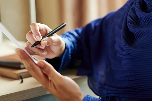 Hands of female muslim teacher checking work of students