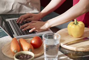 hands of female food . working on laptop when cooking dinner in her kitchen