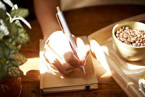 Close-up image of woman writing something on cover of her journal