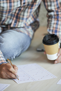 Close-up image of entrepreneur with cup of coffee working with financial document