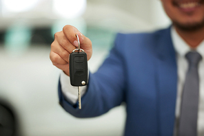 Closeup of car owner holding car key in his hand and showing it to the camera in car showroom