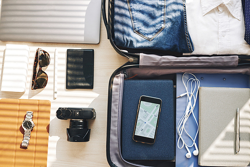 Image of smartphone with map in suitcase and other gadgets on the table