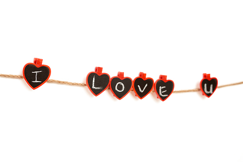 Clothes pegs with I LOVE YOU phrase written with chalk attached to rope on white background