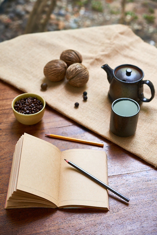 Image of empty notebook with colorful pencils, coffee beans and coffee drink on wooden table
