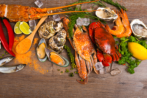 Ice-cold seafood and seasonings aranged on wooden background