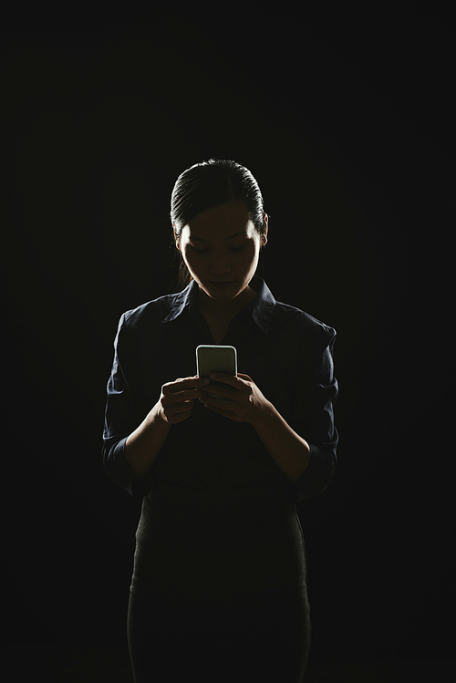 Business lady in dim light answering text messages
