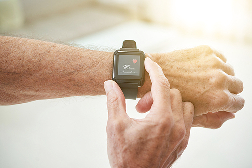 Crop shot of elderly man measuring pulse with modern smart watch in sunlight