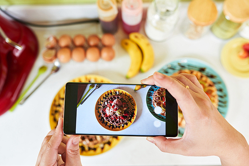 Hand of person taking photo of dessert on smartphone