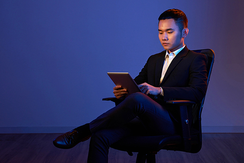 Young confident entrepreneur reading information on tablet computer