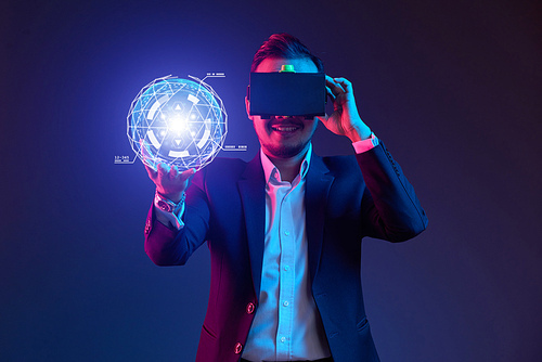 Smiling businessman in virtual reality glasses enjoying graphical user interface