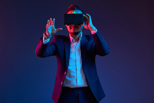 Smiling businessman using virtual reality headset in darkness