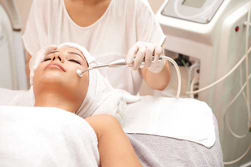 Young client of spa salon having relaxing procedure for facial skin rejuvenation