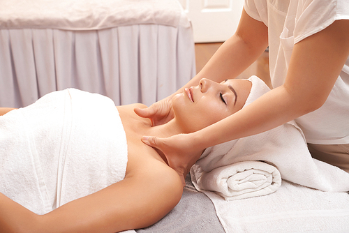 Beautiful young woman enjoying relaxing massage procedure in spa salon
