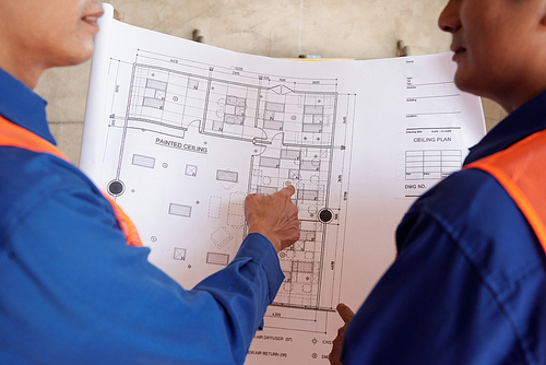 Professional construction workers discussing blueprint of building