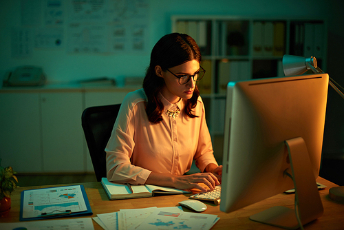 Young business woman working on computer in dark office