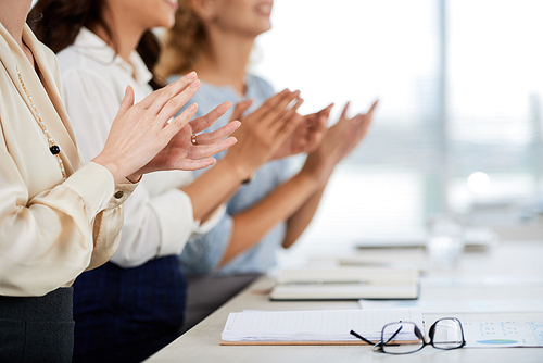 Business women clapping to speaker at conference