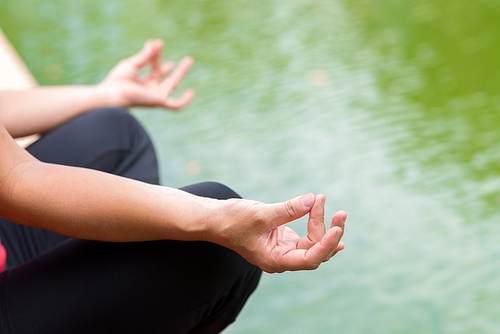 Cropped image of sporty woman meditating in lotus position