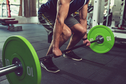 Cropped image of sportsman practicing deadlift with heavy weight