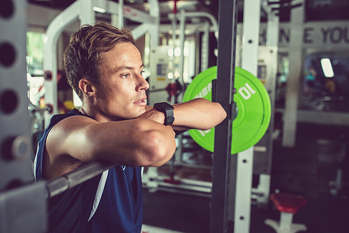 Handsome sporty young man having short break after lifting weight