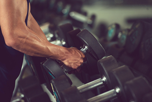 Strong sportman choosing dumbbell to exercise with from row