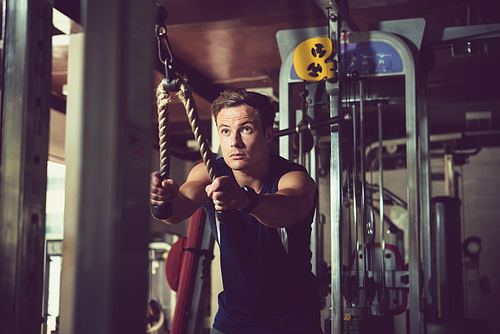 Athletic man doing exercise in crossover machine