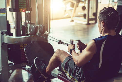 Young fit man working out on simulator in gym